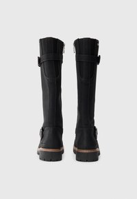 Schwarze, kniehoche Stiefel aus Leder mit glatter Textur, seitlichem Reißverschluss und verstellbaren Riemen. Robuste, gerippte Gummisohle mit brauner Ziernaht.