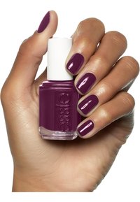 Bottiglia di smalto Essie di colore viola con tappo bianco, tenuta in mano che mostra unghie abbinate e laccate. Finitura liscia, texture lucida.