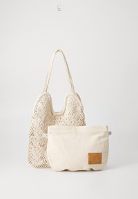 Handcrafted netted tote bag in cream with intricate floral patterns, paired with a soft beige pouch featuring a brown leather accent.