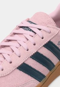 Rosa semsket sko med mørkeblå striper, runde lisser og en såle i gummigummi, med en glatt tekstur og sydd dekor.