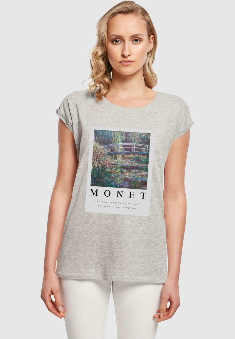 T-shirt gris à manches courtes featuring une œuvre d'art de Monet imprimée avec un pont au-dessus de l'eau, encadrée par un texte en bas. Matériau en coton doux.