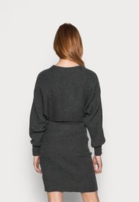 Abito a maglia grigia a coste con maniche lunghe a palloncino, vita aderente e gonna dritta. La vista posteriore mostra una texture morbida e un design semplice.