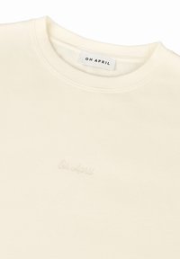 Felpa color crema con colletto a costine, caratterizzata da una sottile ricamo "Oh April" con filo coordinato sulla parte anteriore. Texture liscia.