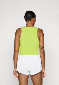 Grøn, ribbet crop top med rund hals, parret med hvide, ribbet shorts med en scallop-finish. Har et tætsiddende design og glat tekstur.