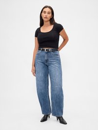 Top corto negro con escote cuadrado, combinado con unos vaqueros de pierna ancha de talle alto en azul y un cinturón negro. Tejido suave y casual.