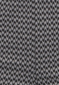 Geometriskt mönstrad tyg med en svart och grå vävd design och en texturerad yta, vilket skapar en subtil kontrast i former.