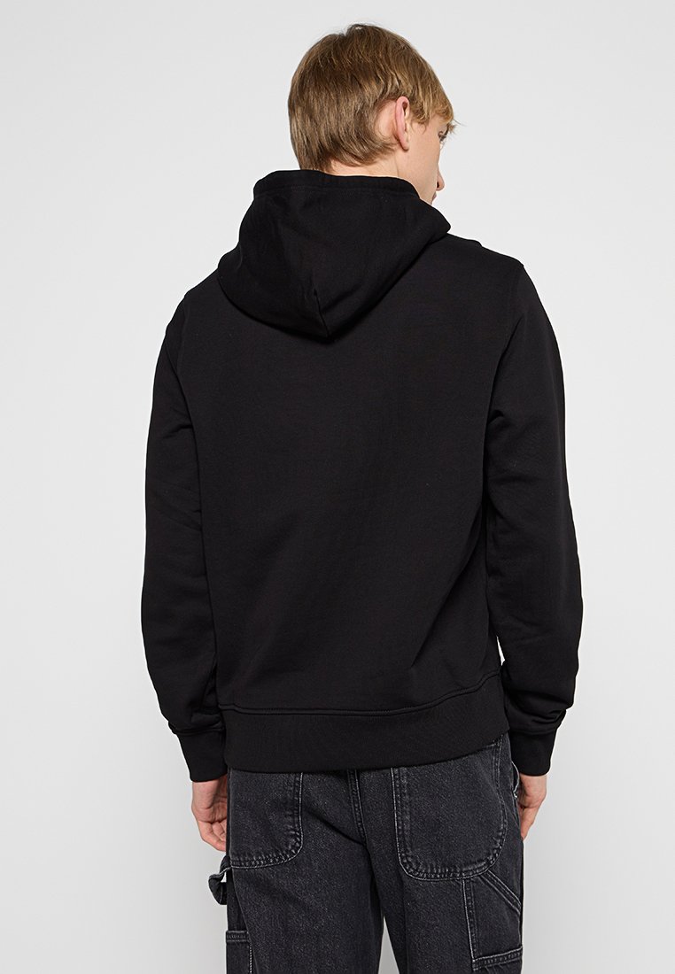 Felpa nera con tasca a marsupio frontale, cappuccio con cordini e polsini a costine. Realizzata in morbido tessuto testurizzato. Design semplice e minimalista.