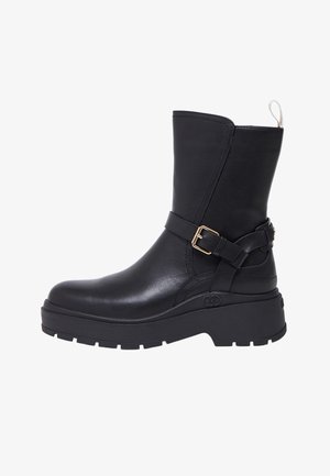 Zwarte leren enkellaarzen met een stevige plateauzool en een zijriemdetail. Gladde textuur; afgerond teenontwerp.