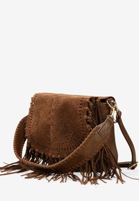 Bolso cruzado de ante marrón con diseño floral recortado, detalles de flecos, correa trenzada y herrajes en tono dorado. Forma compacta y estructurada.