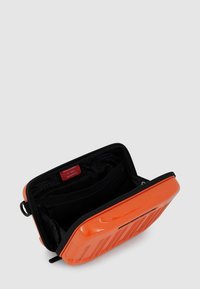 Borsa rigida arancione con esterno testurizzato, caratterizzata da una chiusura con cerniera e interno nero con fodera a motivo e tasca aggiuntiva.