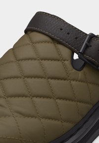 Πράσινο χακί παπούτσι τύπου slip-on με μαύρη σόλα και ρυθμιζόμενο υφασμάτινο σκούρο καφέ λουρί με αγκράφα.