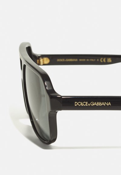 Juodi acetato akiniai nuo saulės su tamsiais objektyvais, turintys lygią apdailą. Rėmeliuose užrašyta "DOLCE & GABBANA" aukso spalva. Pagaminta Italijoje.