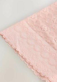 Texturerad rosa tyg med intrikata spetsmönster, vågig kant och geometriska designelement. Mjukt, lätt material med subtila detaljer.