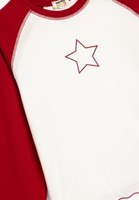 Rot-weißer Baumwollpullover mit Raglanärmeln, der ein rotes Sternenmotiv auf der Brust und kontrastierende Saumnähte aufweist.