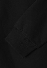 Nahaufnahme von schwarzem Baumwollstoff mit einem gerippten Saum, der eine glatte Textur und minimale Nähdetails aufweist.