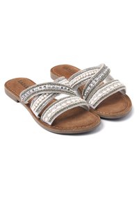 Witte sandalen met een schuine zool, voorzien van meerdere gestructureerde banden met metalen accenten en kralen. Zachte bruine binnenzool met stikseldetails.