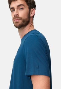 Blue crew-neck T-shirt made of soft cotton blend, featuring short sleeves and a subtle logo detail on the left sleeve.