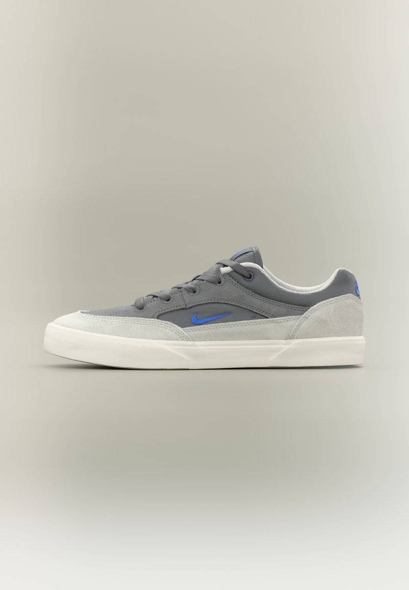 Sivá teniska s kombináciou semišu a hladkých materiálov, modré logo v akcentoch, zaoblená špička, biela gumová podrážka a klasický šnurovací dizajn.