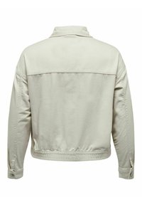 Chaqueta de denim de color beige claro con un corte relajado, cuello estructurado y puños abotonados. Presenta una costura de yugo en la parte posterior y un dobladillo elástico.