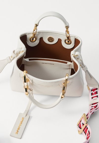 White pebbled leather handbag with gold hardware. The interior features a brown lining and a branded compartment. Includes a detachable strap.