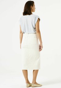 Falda midi de mezclilla blanca con bolsillos traseros, que presenta un diseño limpio y una textura suave. Combinada con una camisa de manga corta azul claro.