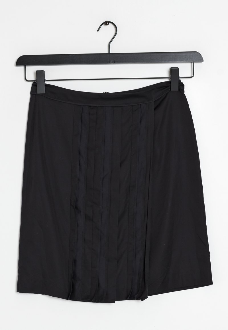 Zwarte rok van gladde stof, met verticale plooien en een platte tailleband. Hangt aan een zwarte hanger tegen een witte achtergrond.