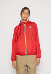 Chaqueta ligera roja con cremallera en el frente, que presenta un acento a rayas a lo largo de la cremallera, capucha y puños elásticos. Logotipo en el pecho.