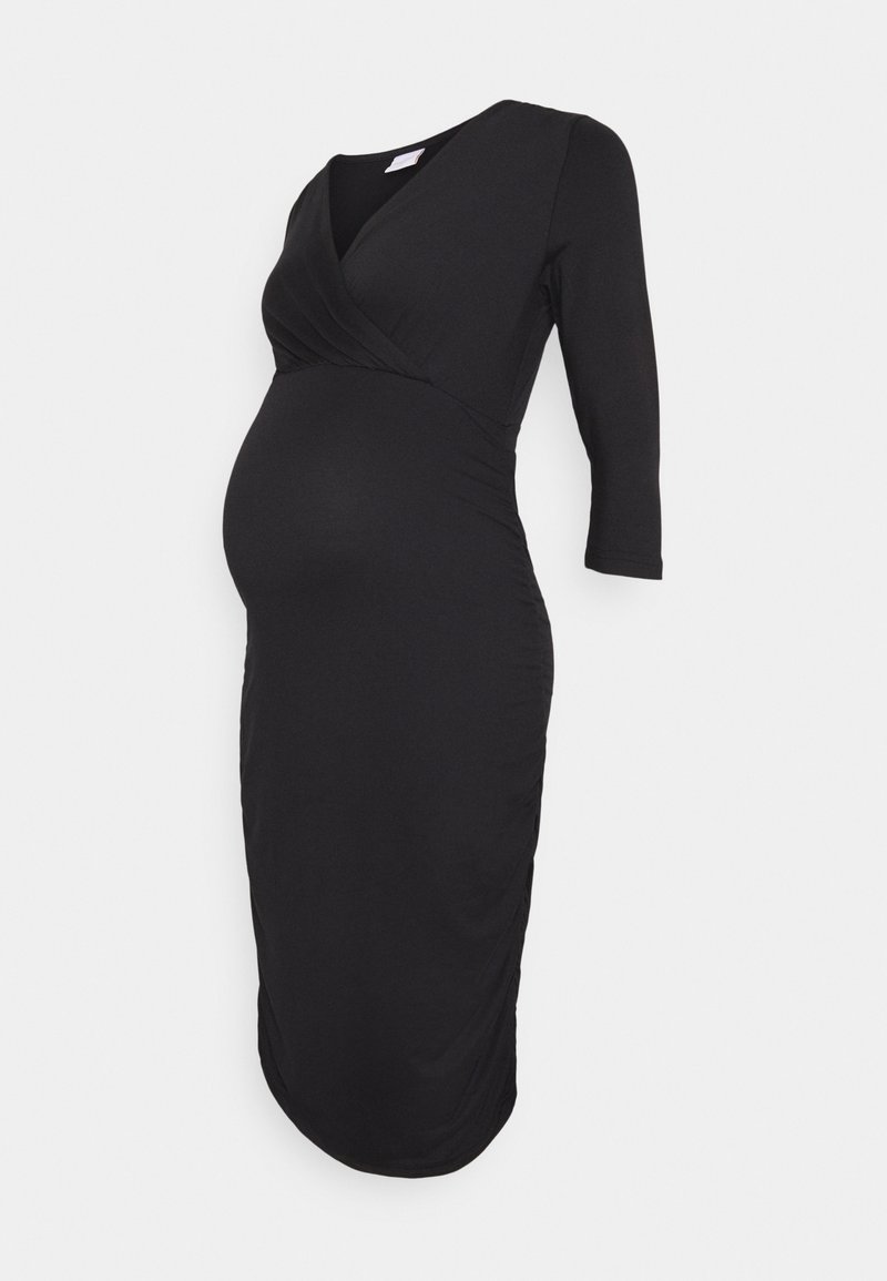Robe de maternité noire longueur genou avec manches 3/4 et col en V portefeuille, ajustée pour mettre en valeur le ventre de la femme enceinte.