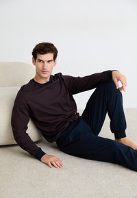 Ensemble de vêtements d'intérieur pour hommes comprenant une chemise à manches longues à motifs dans un bordeaux foncé et un pantalon à poignets élastiques bleu marine, fabriqué dans un tissu doux.