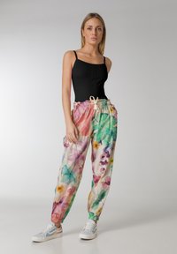 Lätta, dragkedjeförsedda blommiga sweatpants i pastellfärger med avslappnad passform, med en blandning av gröna, rosa och lila bladmönster.