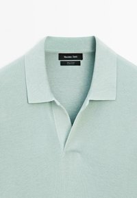 Světle zelená polo tričko vyrobené z 100% bavlny, s texturovanou látkou, límečkem a dvoupanelovým zapínáním na knoflíky. Viditelná značka uvnitř.