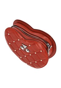 Sac à main en cuir rouge avec un design matelassé, orné de clous argentés et une fermeture éclair. Forme circulaire avec un accent logo sur le devant.