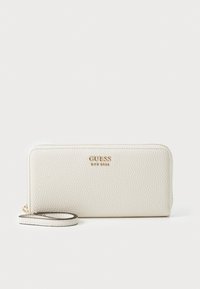 White leather wallet with a textured surface, gold hardware, and a wrist strap. The brand name "GUESS" is embossed on the front.