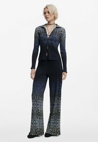 Mørkeblå ribbet todelt outfit bestående af en knappet skjorte og flagrende bukser med et cirkulært mønster, der skifter til lysere nuancer.