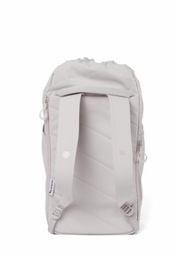 Helle graue Rucksack mit einem Kordelzugverschluss oben, vertikal gestepptem Muster, breiten Schultergurten und seitlichen Reißverschlusstaschen. Robuste Stoffoberfläche.