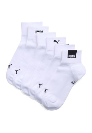 Pięć par białych skarpetek typu ankle marki Puma, ułożonych nakładających się na siebie, każda z czarnym logo Puma w pobliżu palców i czarnym napisem marki na ściągaczach.