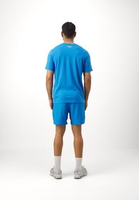 Blaues Sport-T-Shirt und Shorts aus leichtem Material. Das Outfit hat ein einfaches Design mit sichtbaren Nähten und einem Logo auf der Rückseite.