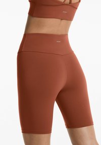 Rostfärgade cykelshorts tillverkade av stretchmaterial, med hög midja och sömlös design för komfort och en jämn passform.