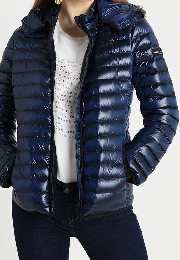 Navy puffer jacket with a glossy finish, featuring a zip closure, a detachable hood, and horizontal stitching. Paired with a printed white shirt.