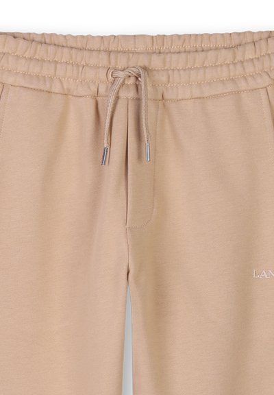 Beige trainingsbroek gemaakt van zacht materiaal, met een elastische tailleband, trekkoord, zijzakken en een klein logo op de dij.