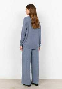 Ensemble de loungewear bleu clair comprenant un haut décontracté à manches longues avec épaules tombantes et un pantalon large. Tissu doux et texturé.