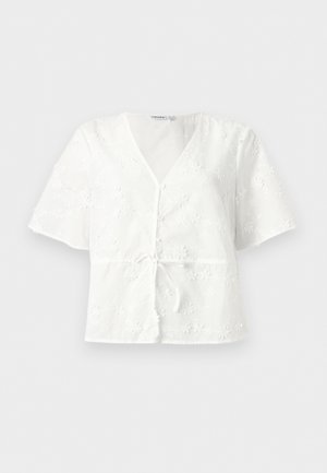 Balta trumpomis rankovėmis palaidinė su V formos iškirpte, mažais priekiniais mygtukais, juosmens dirželiu ir audinyje siuvinėtu gėlių raštu.