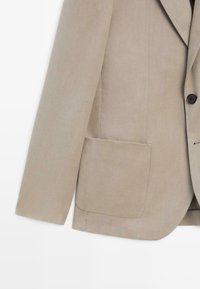 Beige lange mouwen blazer met een borstzak en een zwarte knoop aan de voorkant, weergegeven tegen een witte achtergrond.