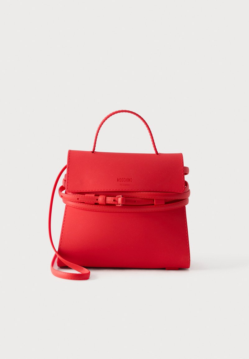 Κόκκινη τσάντα Moschino Milano με επάνω λαβή, μπροστινό καπάκι και μακρύ ρυθμιζόμενο λουρί ώμου, εμφανίζεται σε απλό λευκό φόντο.