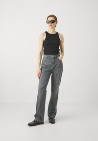 Black tank top, high-waisted light gray jeans, sleek black sunglasses, and black studded shoes. Simple design with a relaxed fit.