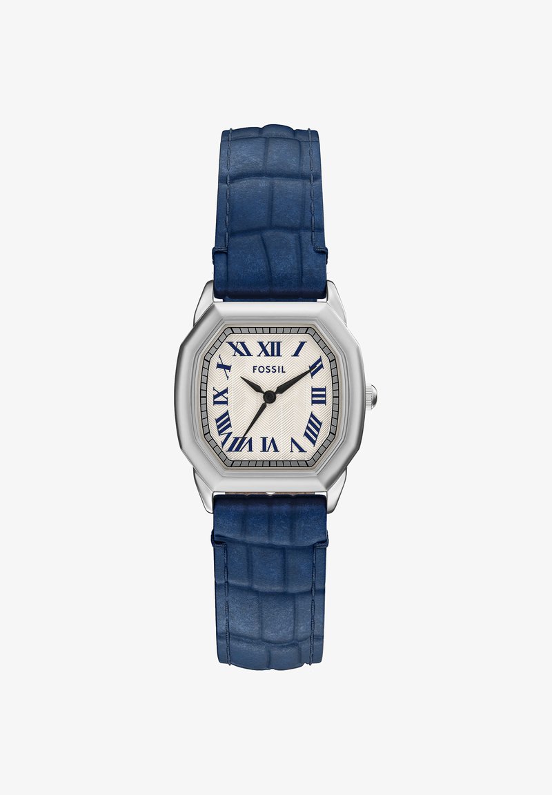 Montre Fossil argentée avec un cadran octogonal, des chiffres romains bleus, un cadran blanc texturé, des aiguilles noires des heures et des minutes, et un bracelet en cuir bleu.
