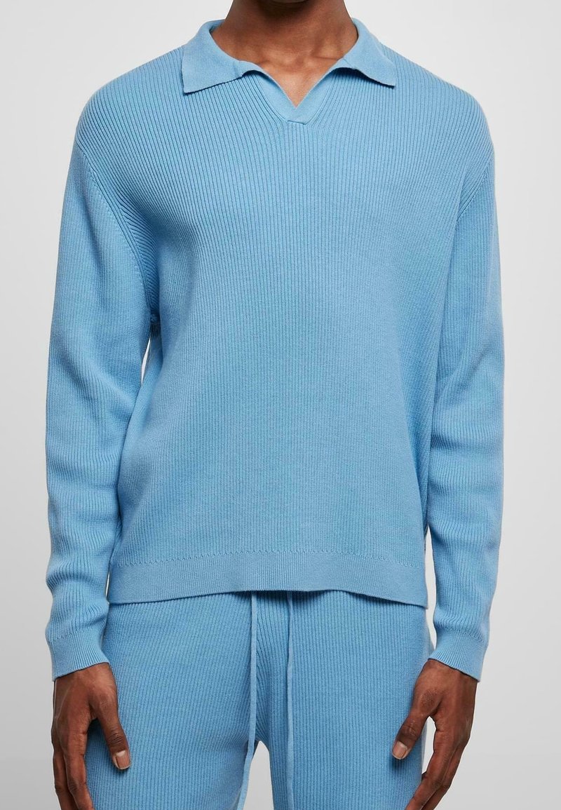Ljusblå, ribbad stickad tröja med V-halsringning och krage. Långa ärmar och avslappnad passform, i kombination med matchande stickade byxor.