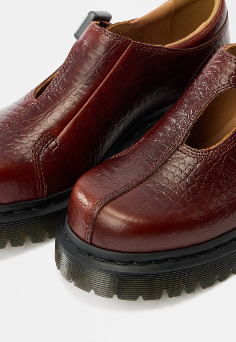 Burgunderrote Lederschuhe mit strukturierter Oberfläche, abgerundetem Zehenbereich und ausgeschnittenen Seiten. Verfügen über eine klobige, schwarze Gummisohle für besseren Halt.