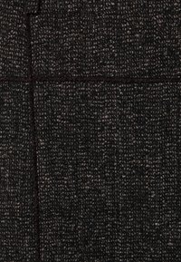 Tela negra texturizada con un patrón tejido en tonos de gris. Incluye costuras visibles que delinean secciones rectangulares.