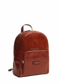 Zaino in pelle marrone con parte superiore arrotondata, scomparto principale con zip, tasca frontale, texture liscia e dettagli in hardware dorato.